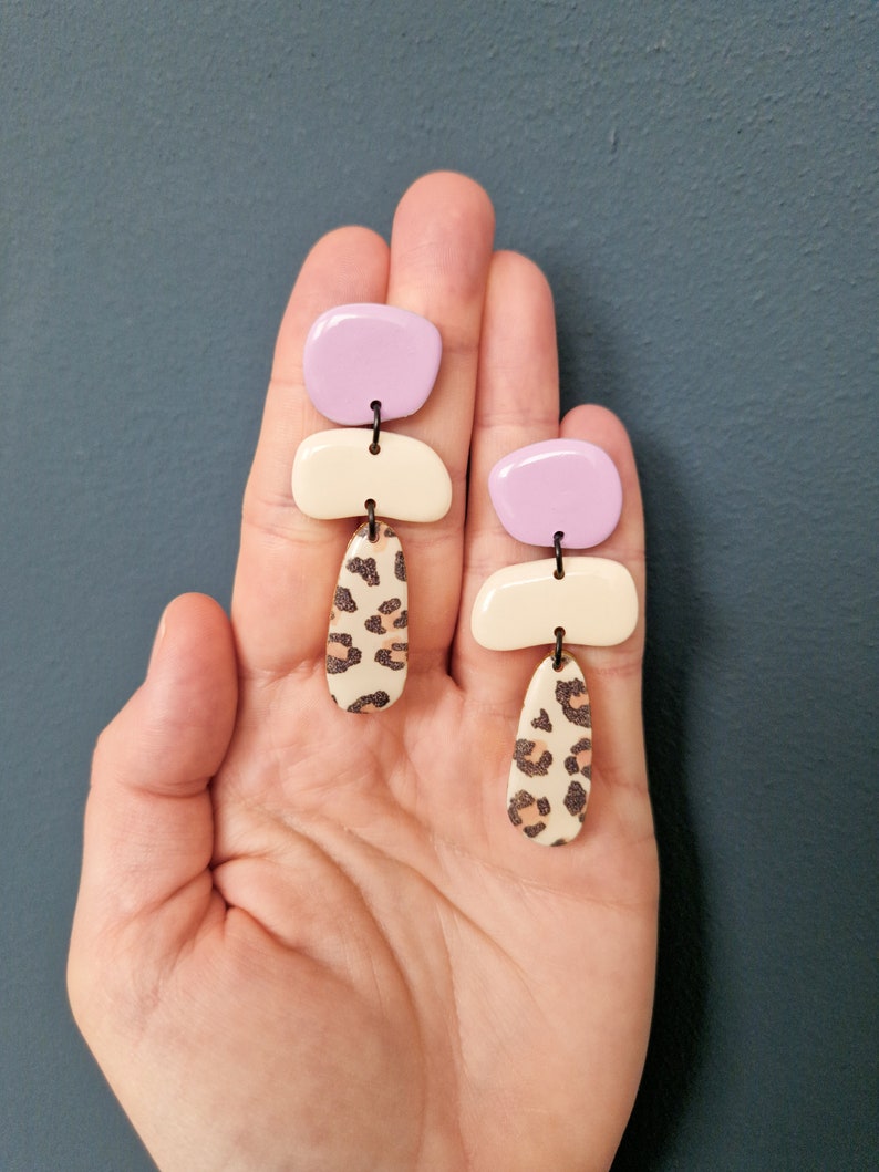 Boucles d'oreilles suspendues en argile polymère motif Cailloux Leo trois pièces crème noir lilas formes géométriques asymétriques bouchon en acier inoxydable Cheetah Bttm. middle Pebbles