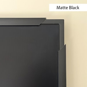 Peut inclure: Gros plan sur un cadre photo noir mat. Le cadre a un design épuré et moderne avec des angles vifs et une finition noire unie. Le texte "Matte Black" est dans un rectangle blanc en haut à droite.