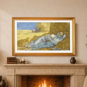 Op de afbeelding: Een ingelijste prent van een schilderij met twee figuren in blauwe kleding die rusten in een tarweveld. Het kunstwerk, in een gouden lijst, hangt boven een open haard. De scène wordt verlicht door warm, natuurlijk licht, met een blauwe lucht op de achtergrond.