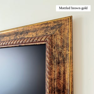 May include: Close-up of a picture frame with a mottled brown-gold finish. The frame has a decorative rope-like design around the edge.