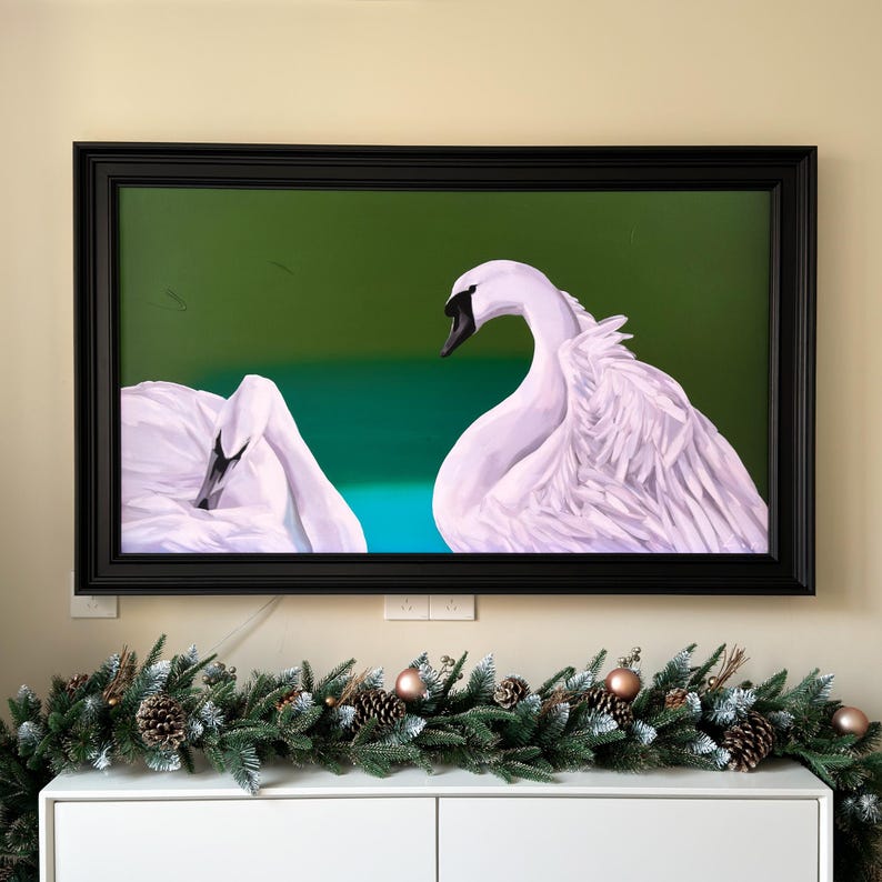 May include: A framed painting of two white swans with black eyes, one swan is facing the viewer and the other is facing away. The swans are on a green and blue background.