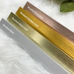 Peut inclure: Quatre bandes métalliques dans différentes finitions : argent brossé, or mat brossé, or titane brossé et or rose brossé.