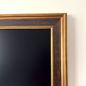 May include: A black chalkboard with a dark brown and gold wood frame. The frame has a decorative, multi-layered design.