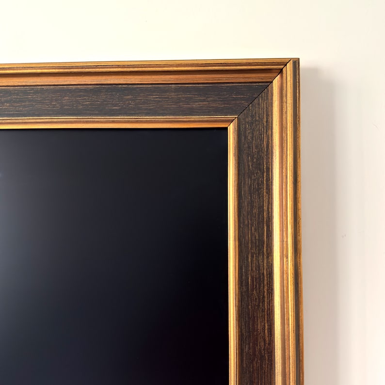 May include: A black chalkboard with a dark brown and gold wood frame. The frame has a decorative, multi-layered design.
