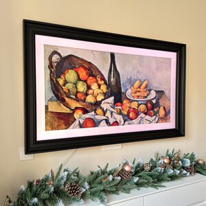 May include: A still life painting of a basket of fruit, a bottle of wine, and a plate of pastries. The fruit is a mix of apples and pears, and the pastries are a light brown color. The painting is framed in a black frame.