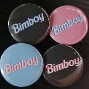 Peut inclure: Quatre boutons ronds avec le mot "Bimbo" dans une police rétro. Les boutons sont noirs, roses, bleus et gris.