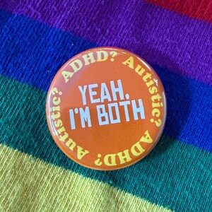 May include: Circular orange badge with the text "YEAH, I'M BOTH" in white. The words "ADHD?" and "Autistic?" are in a circle around the central text. The background is a rainbow pattern.