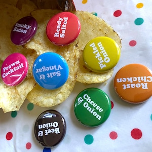 May include: Assortment of colourful round buttons with different flavour combinations for potato chips. The flavours include:  Smoky Bacon, Ready Salted, Prawn Cocktail, Salt & Vinegar, Pickled Onion, Cheese & Onion, Beef & Onion, and Roast Chicken.