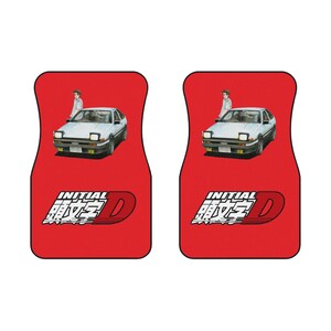 May include: Pair of red car floor mats featuring a white car graphic with a person standing next to it. The mats also have the text "INITIAL D" in white.