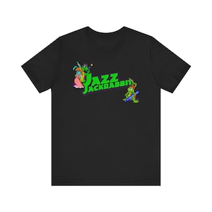 May include: Black t-shirt with the words "Jazz Jackrabbit" in green and yellow, accompanied by cartoon characters. The design includes a green rabbit playing a saxophone and other animated figures.