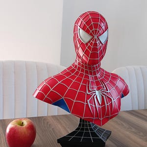 May include: A red and blue Spider-Man bust with a black web-shaped base. The bust is a collectible figure of the superhero.