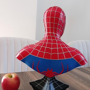 May include: A red and blue Spider-Man bust with a web design. The bust is on a black base with a web design.