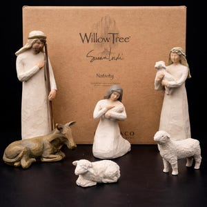 Puede incluir: Un conjunto de nacimiento de Willow Tree con seis figuras: un pastor, María, José, un burro y dos ovejas. Las figuras son en tonos neutros, con una textura tallada. El fondo es una caja de cartón marrón con las palabras "Willow Tree Susan Lordi Nativity".