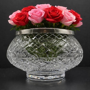 May include: A crystal glass bowl with a silver rim, filled with red and pink roses. The bowl has a diamond-cut pattern and sits on a clear base, creating a beautiful floral arrangement.