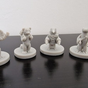Peut inclure: Quatre figurines miniatures peintes en gris de différents animaux, chacune debout sur une base ronde. Les animaux sont un lézard avec une collerette, un ours, un oiseau et une belette.