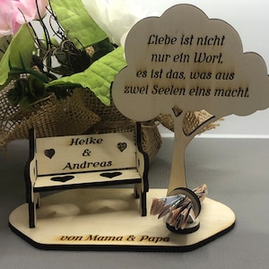 May include: A wooden bench with the names Heike & Andreas engraved on it, a wooden tree with the quote "Liebe ist nicht nur ein Wort, es ist das, was aus zwei Seelen eins macht." and the text "von Mama & Papa" on a wooden base.