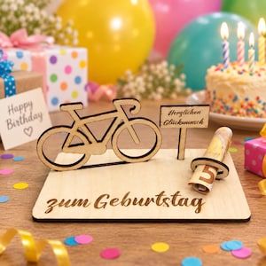 Può includere: Un espositore di compleanno in legno chiaro con una sagoma di bicicletta, un cartello con il testo "Herzlichen Glückwunsch" e una base incisa con "zum Geburtstag". Una banconota da cinque euro arrotolata è inserita in un supporto circolare.