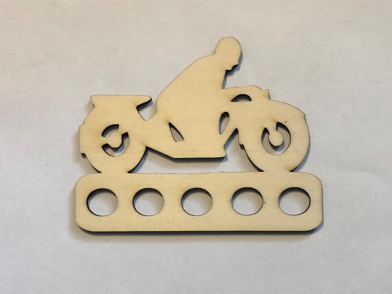 Peut inclure: Mod&egrave;le de moto en bois avec six trous pour tenir les aiguilles &agrave; tricoter. La moto est de style silhouette et est en bois brun clair.