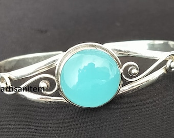 Könnte beinhalten: Ein silbernes Armband mit einem großen, runden, hellblauen Edelstein. Das Armband hat einen dekorativen Rahmen und Schnörkel. Der Text "silverartisanitem" ist sichtbar. Ein schönes Schmuckstück.