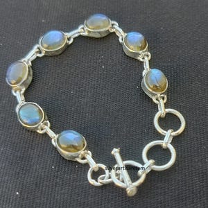 以下が含まれることがあります： 留め具付きのシルバーブレスレットは、楕円形のラブラドライトの宝石がついたチェーンが特徴です。ブレスレットはスターリングシルバー製で、磨かれた仕上げになっています。