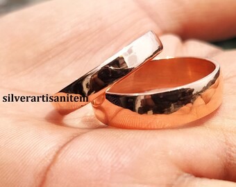 May include: Two rose gold wedding bands with a hammered finish. The bands are stacked on top of each other.