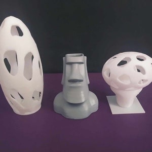 May include: Three 3D printed sculptures: a white egg-shaped object with holes, a grey bust of a face with a nose and mouth, and a white mushroom-shaped object with holes.