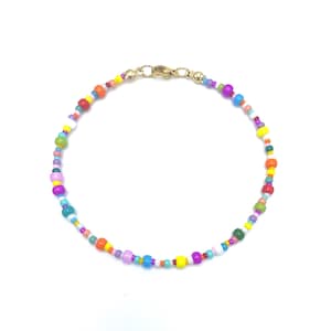 Peut inclure: Un bracelet de perles colorées avec un fermoir doré. Le bracelet est composé de petites perles rondes de couleurs rouge, orange, jaune, vert, bleu, violet et blanc. Les perles sont enfilées pour former un accessoire délicat et vibrant.