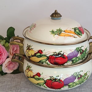May include: A set of two white enamel pots with brass handles and lids. The pots are decorated with a colourful vegetable design and the words "Sweet Corn" and "Green Beans".