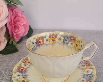 May include: A vintage teacup and saucer set with a floral pattern. The cup and saucer are white with a gold trim and feature a border of colorful flowers.