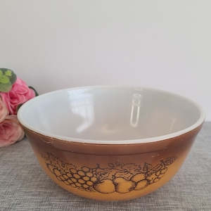 Puede incluir: Un tazón de mezcla marrón y blanco con un diseño de fruta. El tazón tiene un interior blanco y un exterior marrón con un diseño de fruta marrón y blanco.