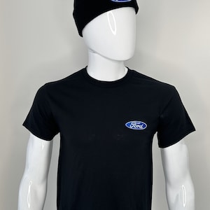 May include: A black t-shirt featuring a blue Ford logo on the front. The shirt is being modelled by a white mannequin wearing a black beanie with a blue Ford logo.