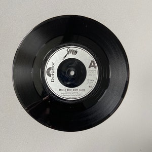 May include: A black vinyl record with a silver label. The label has the text "Polydor", "Shang", "A", "Singature Publishing", "2059 023", "1978", "Polydor Limited UK", "Angels With Dirty Faces", "Pursey/Parsonal", "Engineered by Peter Wilson", "Produced by Jimmy Parsey", and "45".