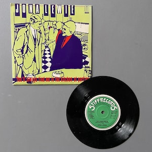 May include: A black and white 7-inch vinyl record with a green label. The label has the text "Stiff Records" in red and white. The record is titled "You'll Always Find Me In The Kitchen At Parties" by Jona Lewie.