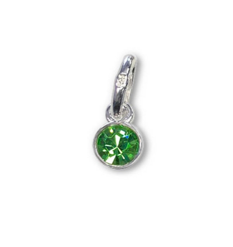 May include: A small, round, green gemstone charm with a silver-colored bail. The gemstone is faceted, reflecting light. The charm is designed to be attached to a bracelet or necklace.