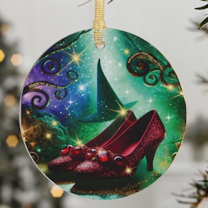 May include: Round Christmas ornament featuring a fantasy scene with ruby red high-heeled shoes, a witch's hat, and swirling green and blue colors. The ornament has gold hanging ribbon and text that reads "Magic is real".