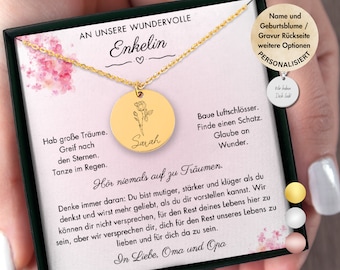 May include: A gold necklace with a round pendant featuring a rose and the name "Sarah" engraved on it. The necklace comes in a black box with a white card that reads "An unsere wundervolle Enkelin" and includes a message about dreams and love. The card also includes the text "Hör niemals auf zu Träumen."