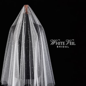 May include: A sheer white bridal veil draped over a mannequin, featuring scattered small white pearls throughout the fabric. The text White Veil BRIDAL is printed in white on the right side against a solid black background.