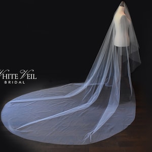 May include: A long, sheer white bridal veil draped over a mannequin, extending across the floor in a circular train. The text White Veil BRIDAL is printed in white on the left side against a dark background, showcasing the elegant, flowing fabric.