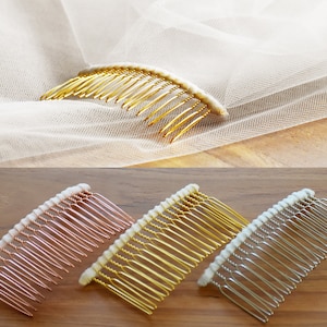 May include: A gold-toned hair comb attached to a sheer white veil, alongside three additional hair combs in rose gold, gold, and silver tones. Each comb features a row of thin metal teeth and a white fabric-wrapped top edge for secure placement.