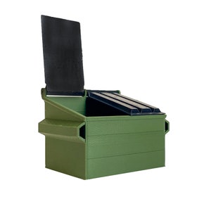May include: A miniature green dumpster with a black lid. The lid is open, revealing the inside of the container. The dumpster is made of a solid material and has a rectangular shape. The design is simple and functional.