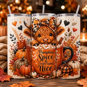 Op de afbeelding: Een cilindrische beker met rietje voorzien van een afbeelding van een pluizige hooglandkoe met een geruite strik, zittend in een grote oranje mok gevuld met slagroom. De mok toont de tekst Pumpkin Spice & EVERYTHING Nice, omringd door pompoenen, herfstbladeren en hartjes.