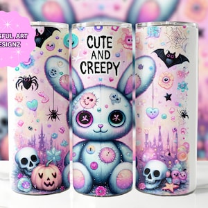 Puede incluir: Un vaso de acero inoxidable blanco con un dise&ntilde;o rosa y azul que presenta un lindo conejito azul cosido con nariz y ojos rosas. El fondo incluye un castillo, corazones, estrellas, ara&ntilde;as y un murci&eacute;lago. El texto "Cute and Creepy" est&aacute; impreso en el vaso.
