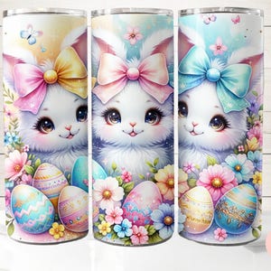 May include: Three white Easter bunny tumblers with colorful bows and Easter eggs. The tumblers are decorated with pastel flowers and butterflies.
