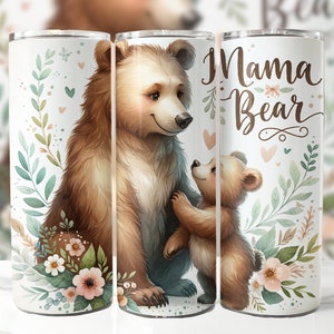 May include: A white tumbler with a brown bear and a smaller brown bear cub. The bears are surrounded by green leaves and pink flowers. The text "Mama Bear" is written in brown cursive on the tumbler.