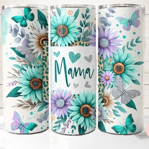 May include: A white tumbler with a floral design featuring teal, purple, and silver butterflies. The tumbler has the word "Mama" in a heart-shaped design.