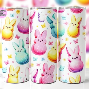 Puede incluir: Tres vasos blancos con un patrón de conejito rosa pastel, azul y amarillo. Los conejos sostienen un dulce parecido a un malvavisco. El patrón se repite en cada vaso.