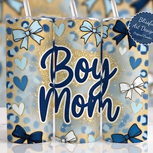 May include: A tumbler with a blue and gold leopard print design. The tumbler features the words "Boy Mom" in navy blue script, along with blue and white bows and hearts. The design includes a straw.