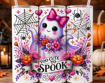 Könnte beinhalten: Ein weißer zylindrischer Becher mit transparentem Strohhalm, verziert mit einem Geist mit rosa Schleife, umgeben von Spinnenweben, orangefarbenen Kürbissen und bunten Blumen. Ein Banner zeigt den Text Too Cute To Spook in schwarzen Buchstaben.