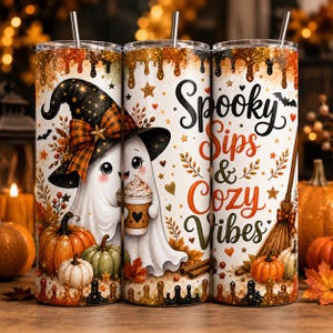 Può includere: Un bicchiere cilindrico con cannuccia raffigurante un fantasma bianco con un cappello da strega nero, che tiene in mano una tazza di caffè. Il design include zucche arancioni e verdi, foglie autunnali, una scopa e il testo Spooky Sips & Cozy Vibes.