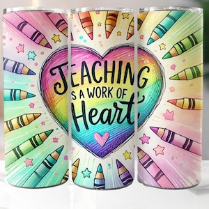 May include: A colorful tumbler featuring a heart-shaped design with the text "Teaching is a Work of Heart." The design includes a rainbow gradient, crayons, and stars. The tumbler is cylindrical and has a silver lid.